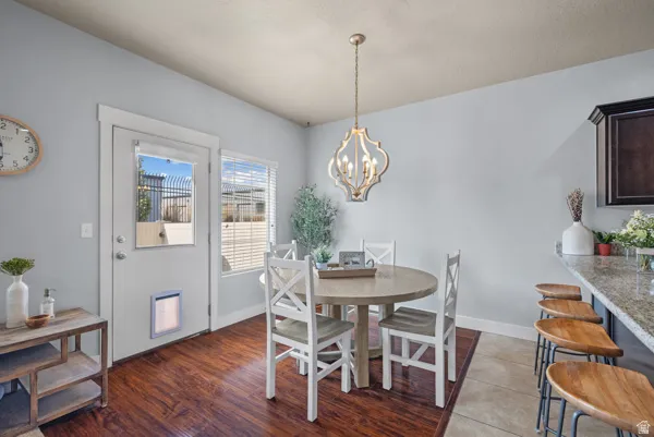 Formal dining area featuring wood-finish flooring, a contemporary chandelier, and a breakfast bar with stone-finish countertops