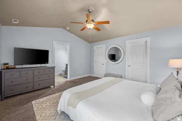 Vaulted ceilings with a ceiling fan, light blue wall paint, and brown carpet flooring