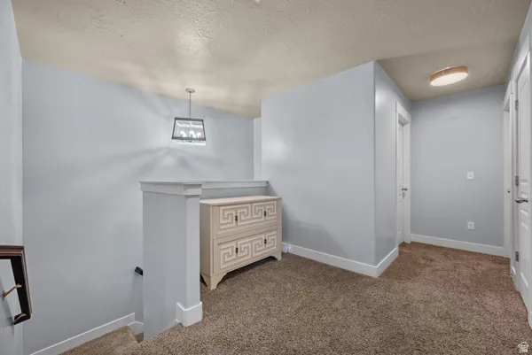 Upper-level landing featuring textured beige carpeting, light blue walls, white trim, and multiple white paneled doors