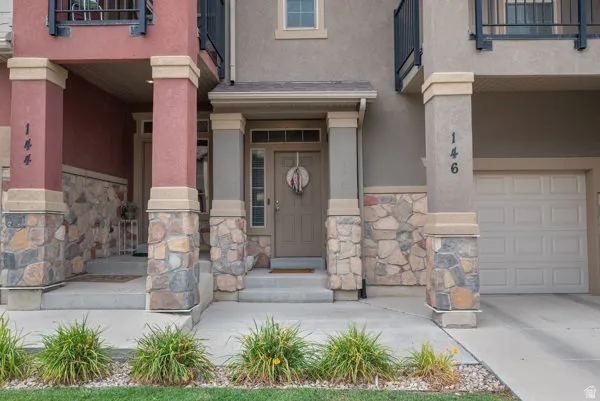 Stone and stucco exterior featuring a covered entry, single-panel front door with sidelights, and an attached garage