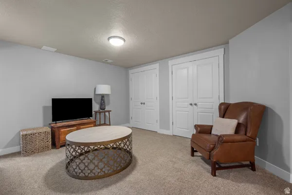 Carpeted room featuring light gray walls, white trim, recessed ceiling lighting, and two sets of white bifold closet doors