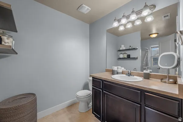 Bathroom vanity featuring a single basin, dark wood-finish cabinetry, and a light-toned countertop