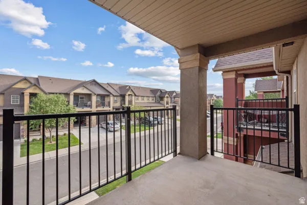 Private balcony featuring a concrete floor, black metal railing, and a textured stucco pillar