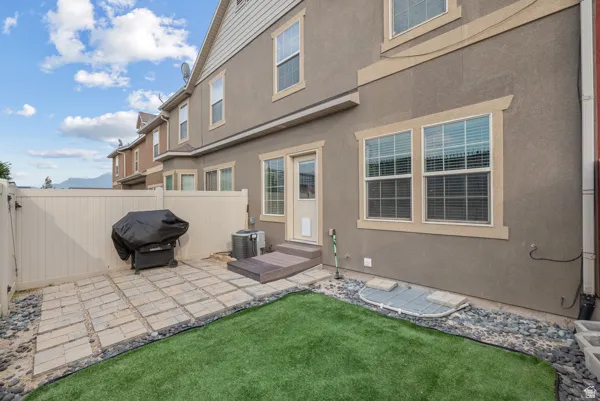 Private outdoor patio featuring paver flooring and a synthetic lawn area