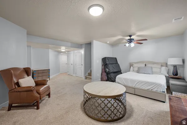 Spacious room featuring neutral carpeting, light-toned walls, and a ceiling fan with integrated lighting