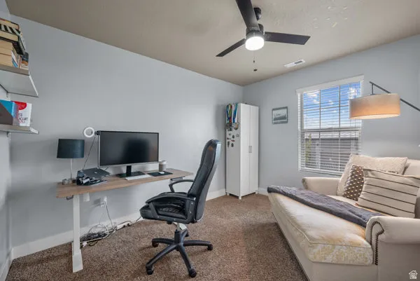 Room featuring neutral wall colors, textured carpeting, a multi-pane window with blinds, and a ceiling fan with integrated lighting