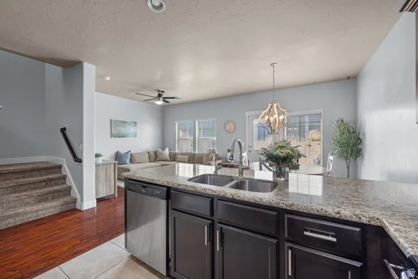 Kitchen island featuring a double basin stainless steel sink, stainless steel dishwasher, and stone-finish countertop