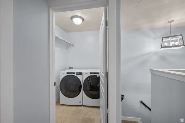 Dedicated laundry area featuring a front-loading washer and dryer, overhead shelving, recessed ceiling light, and tile flooring