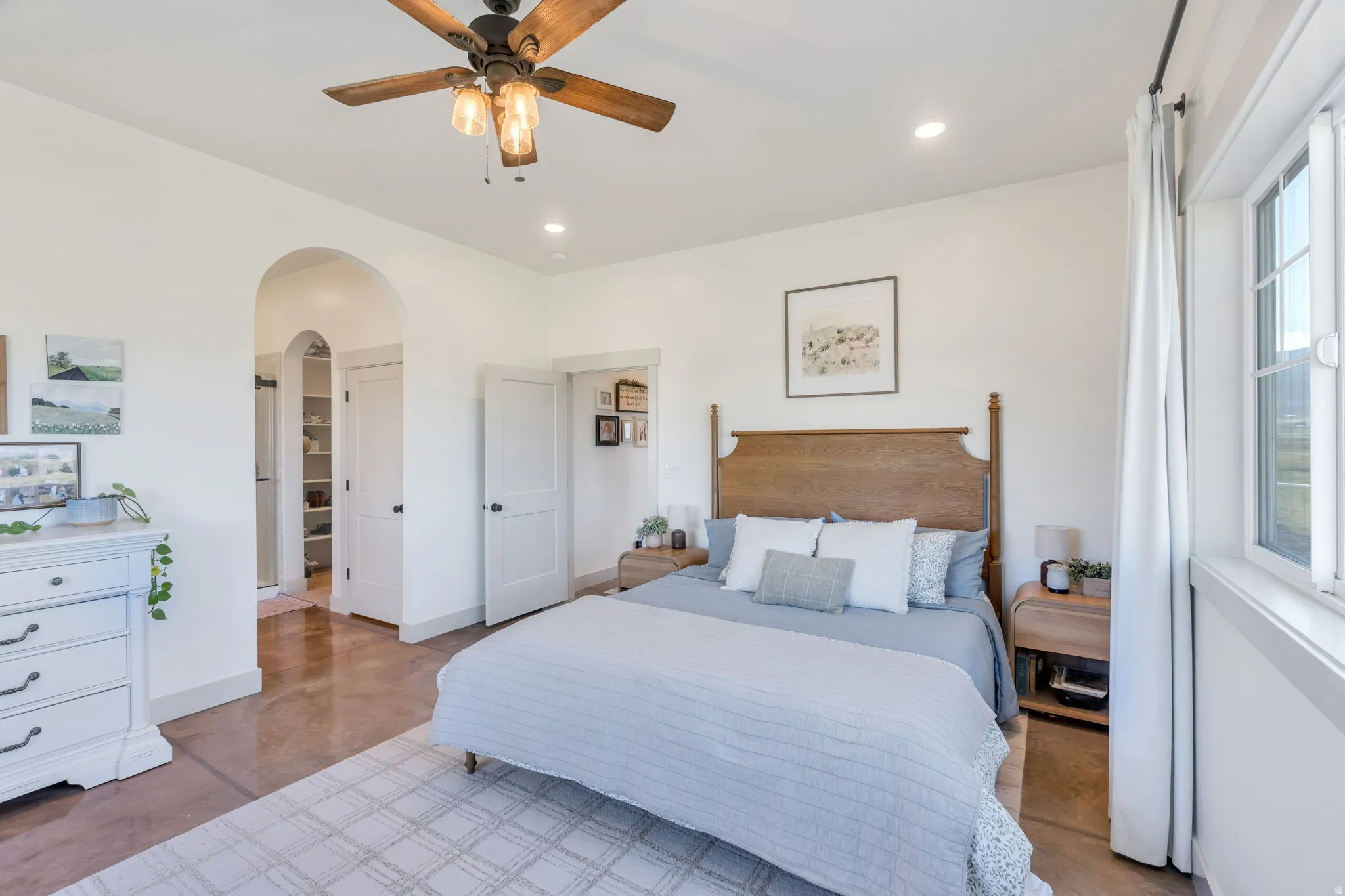 Spacious room featuring wood-finish flooring, a ceiling fan with integrated lighting, recessed lighting, and an arched doorway