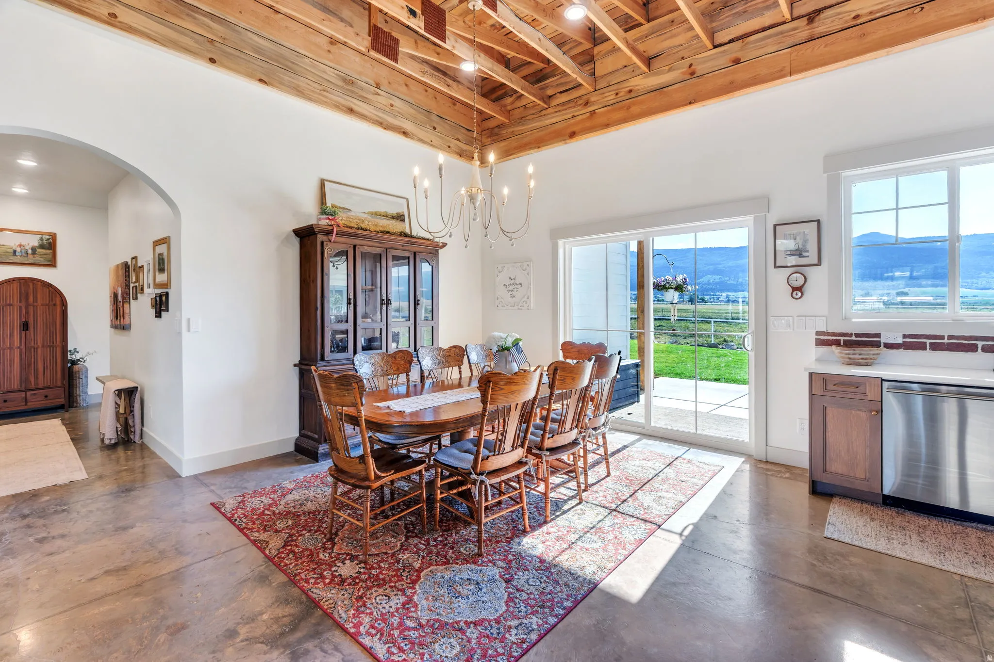 Spacious dining area featuring a wood beam ceiling, exposed wood joists, a sliding glass door, and a multi-pane window