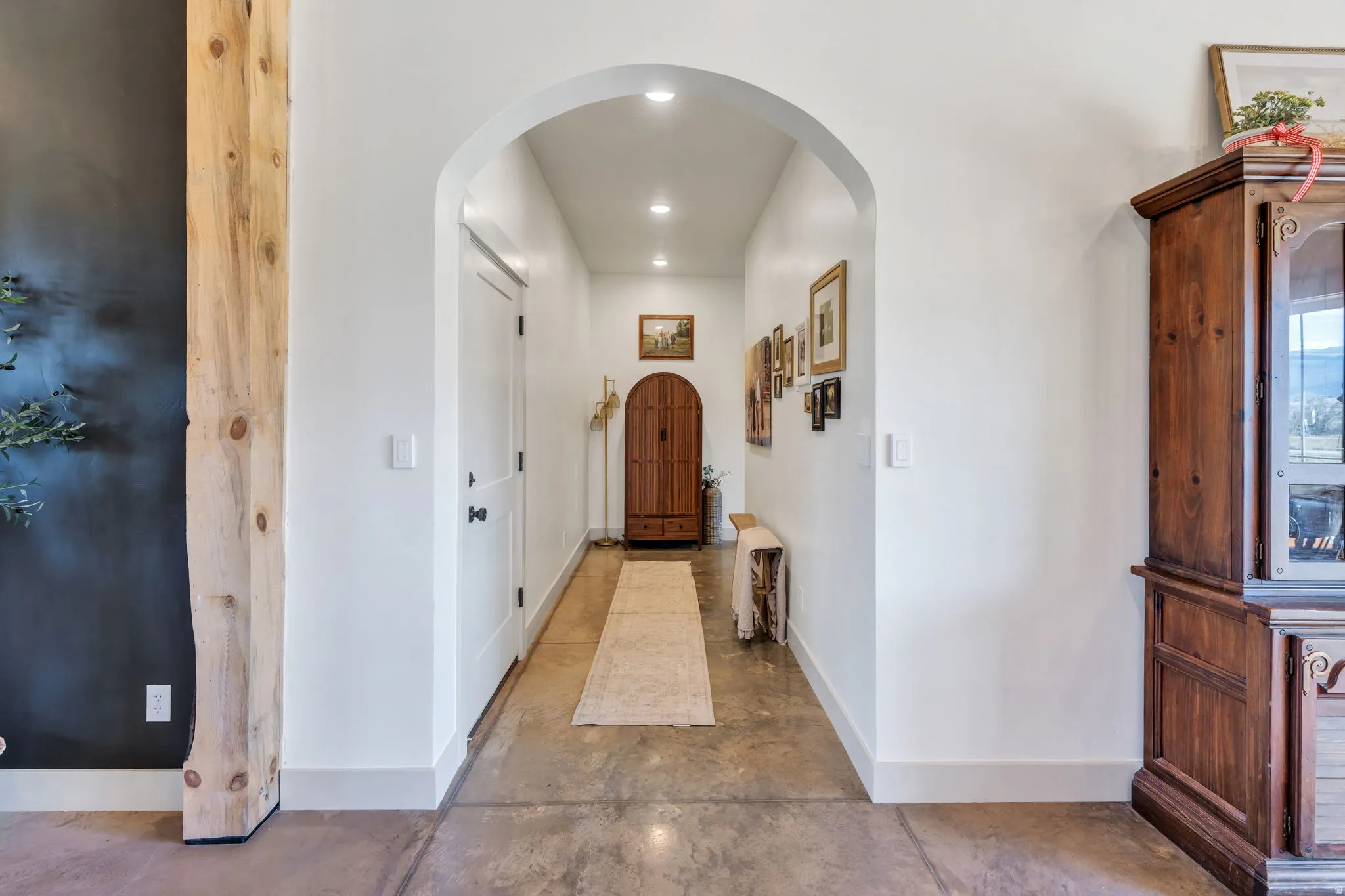 Archway entry to a hallway featuring concrete flooring and recessed lighting