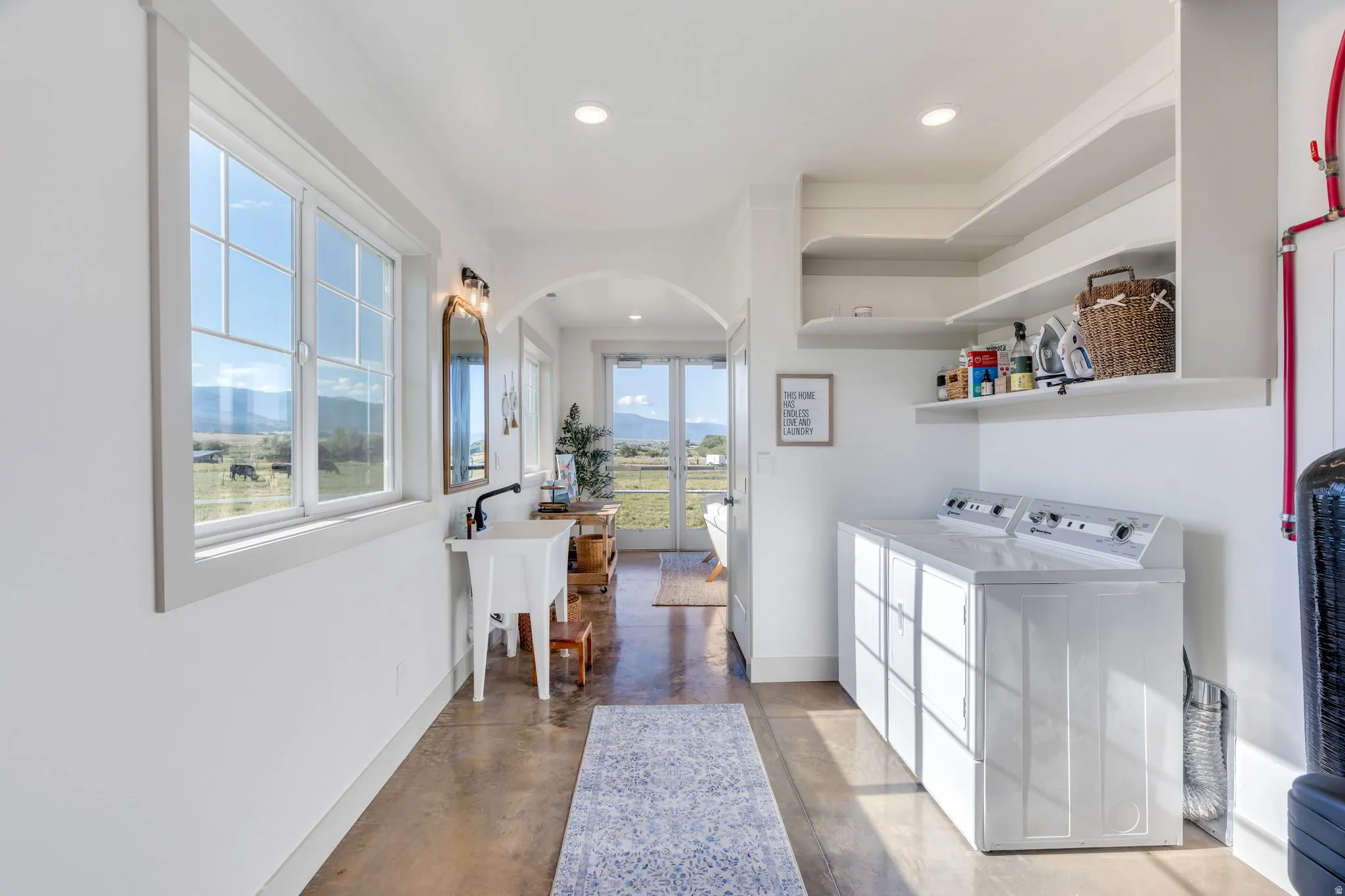 Utility room featuring a utility sink with a wall-mounted faucet, open shelving, and a washer and dryer