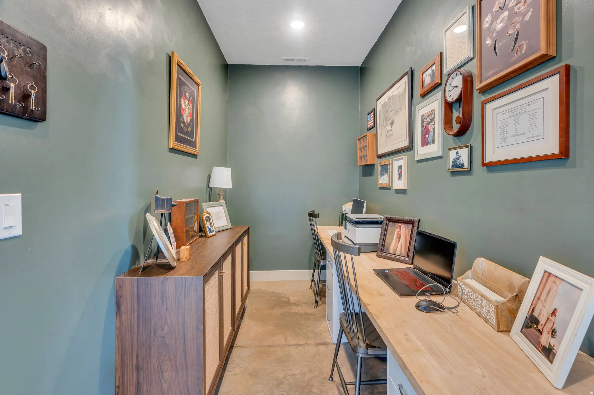 Dedicated workspace featuring a wood-finish countertop, built-in cabinetry with wood-finish doors, recessed ceiling lighting, and concrete-finish flooring