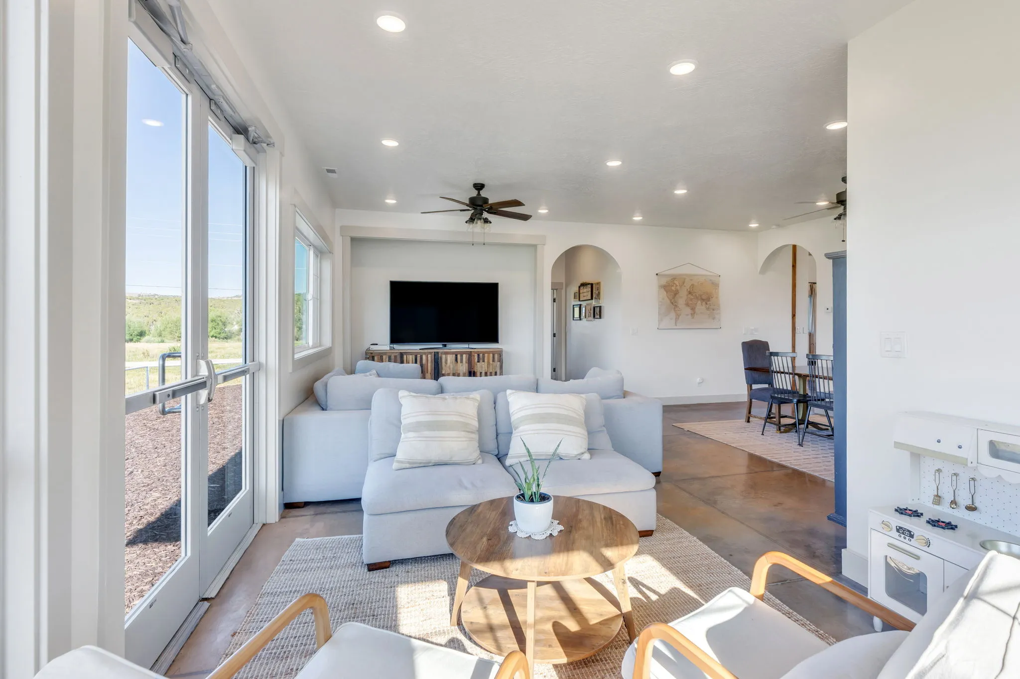 Living area with recessed lighting, ceiling fan, large glass paneled door, and archway openings