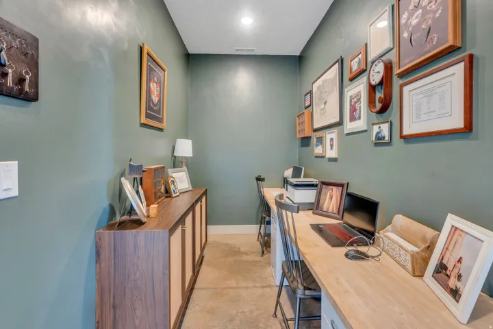 Dedicated workspace featuring a wood-finish countertop, built-in cabinetry with wood-finish doors, recessed ceiling lighting, and concrete-finish flooring