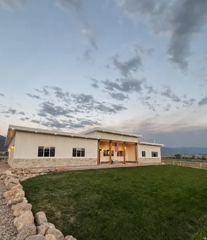 Modern exterior featuring white vertical siding, light-toned stone accents, and an expansive covered porch with wood columns