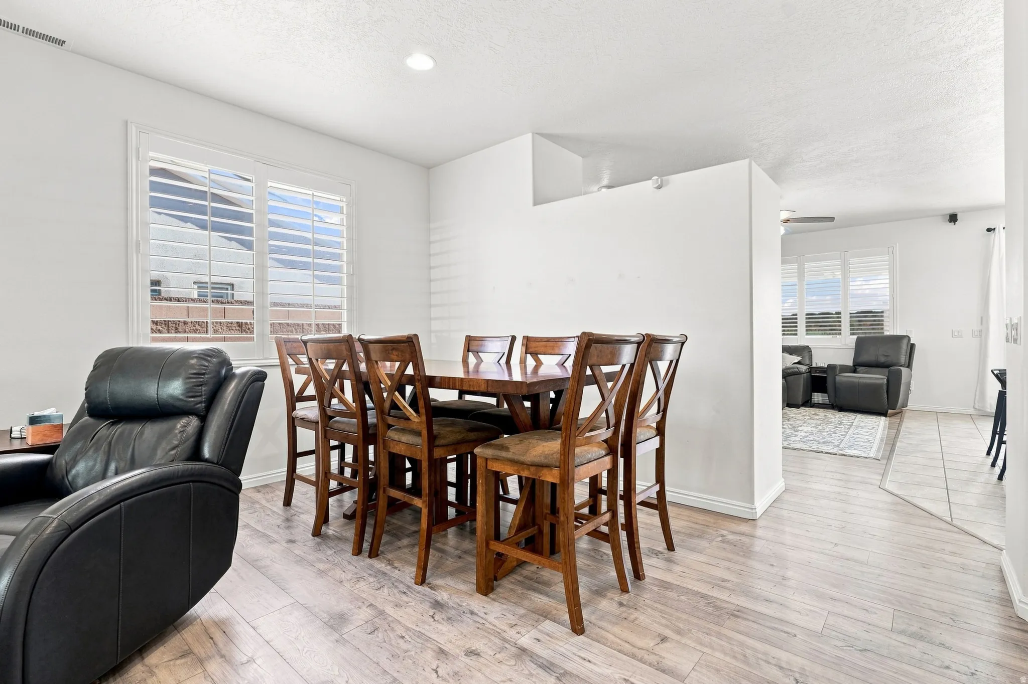 Dining area featuring wood-finish flooring, white walls, recessed lighting, and plantation shutters