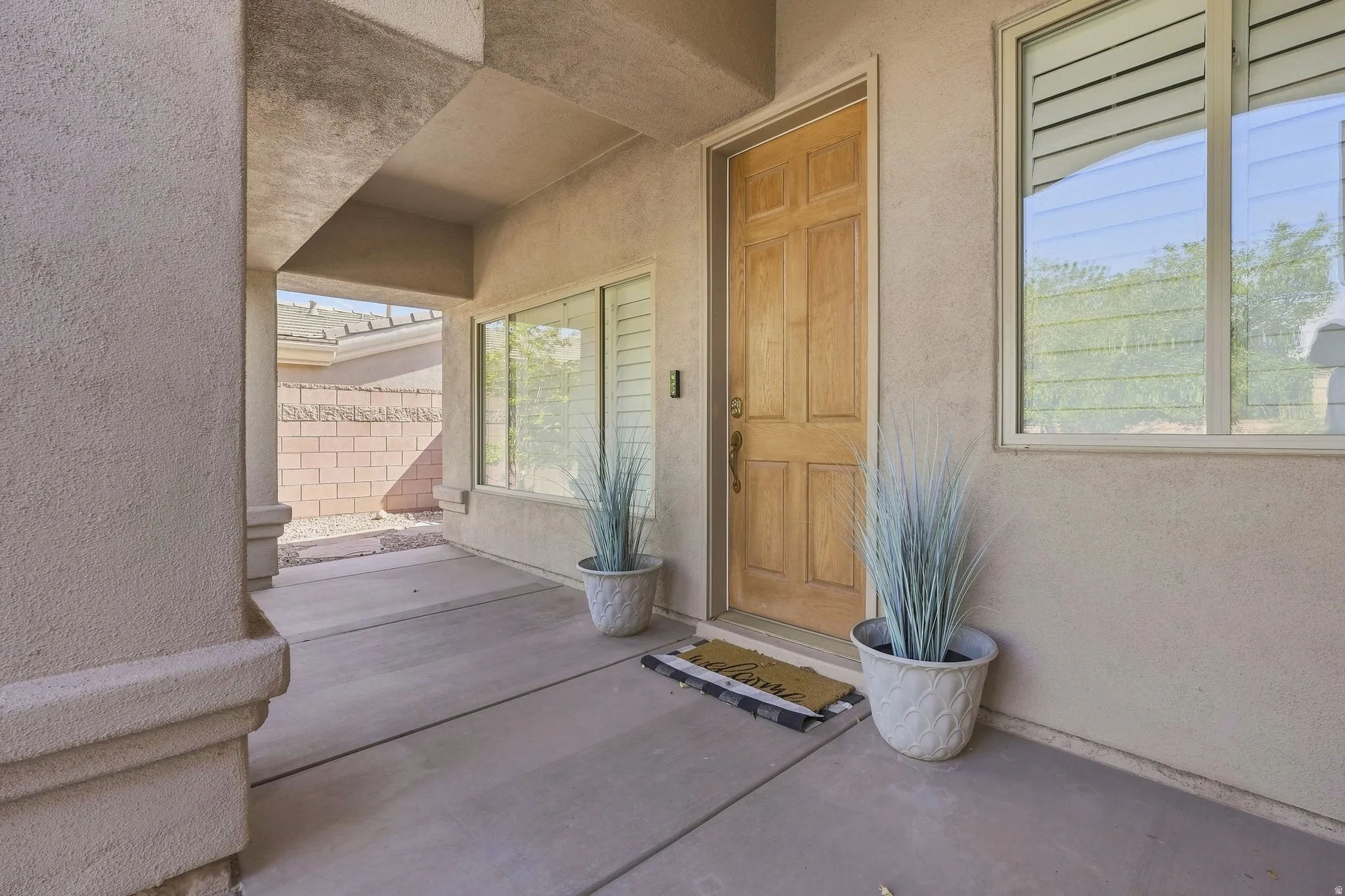 Covered entry featuring a paneled wood door, stucco exterior, and concrete flooring