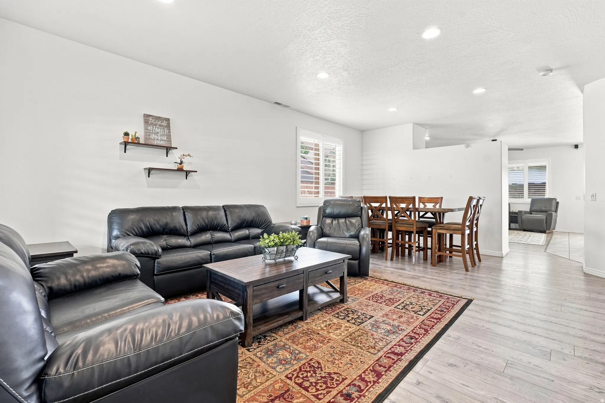 Spacious living area featuring light wood-finish flooring, recessed lighting, and white walls
