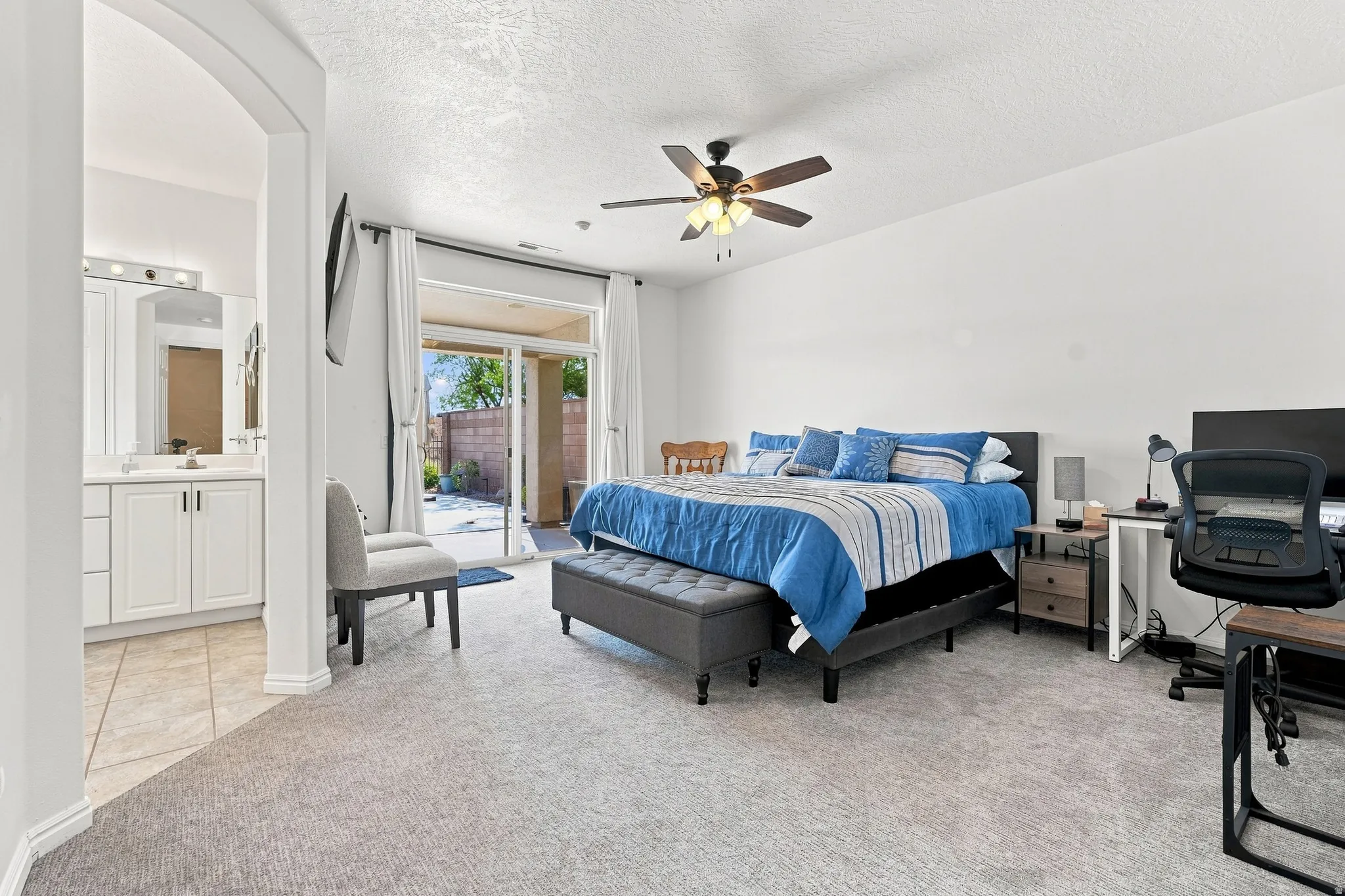 Spacious room featuring light gray carpeting, a ceiling fan, and sliding glass doors opening to an outdoor patio