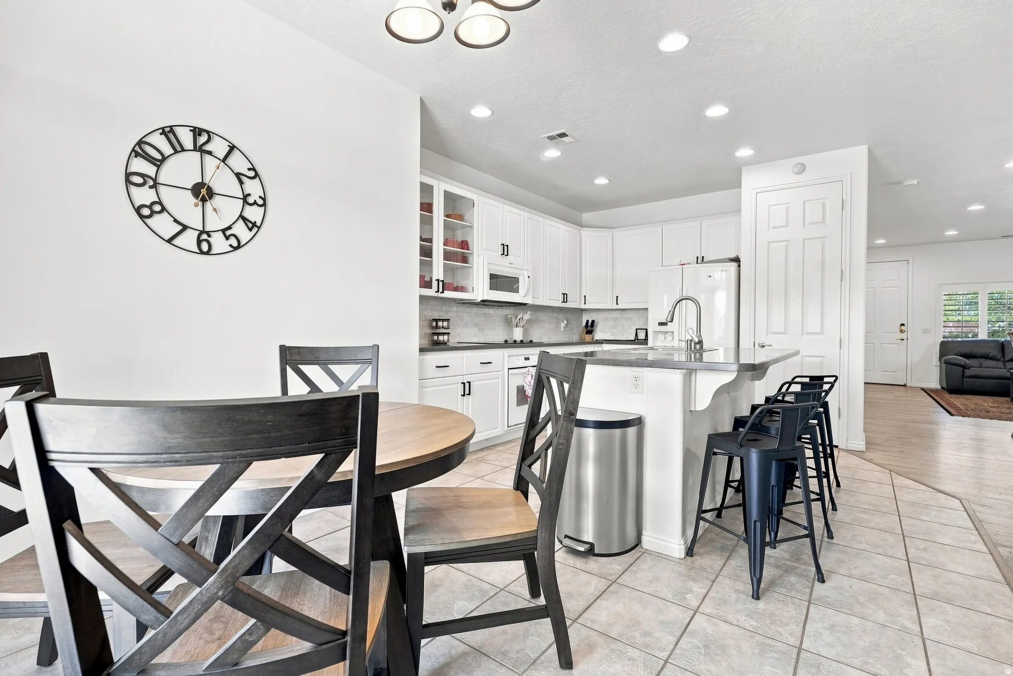 Kitchen featuring white cabinetry, light-toned countertops, a center island with bar seating, a stainless steel sink with a gooseneck faucet, and recessed lighting