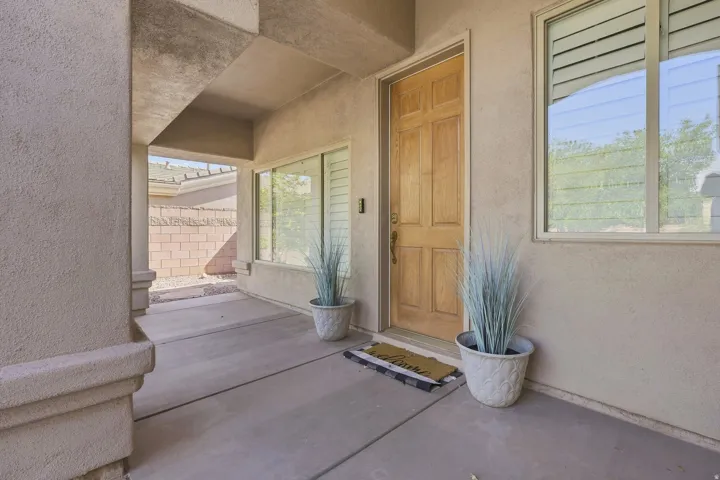 Covered entry featuring a paneled wood door, stucco exterior, and concrete flooring