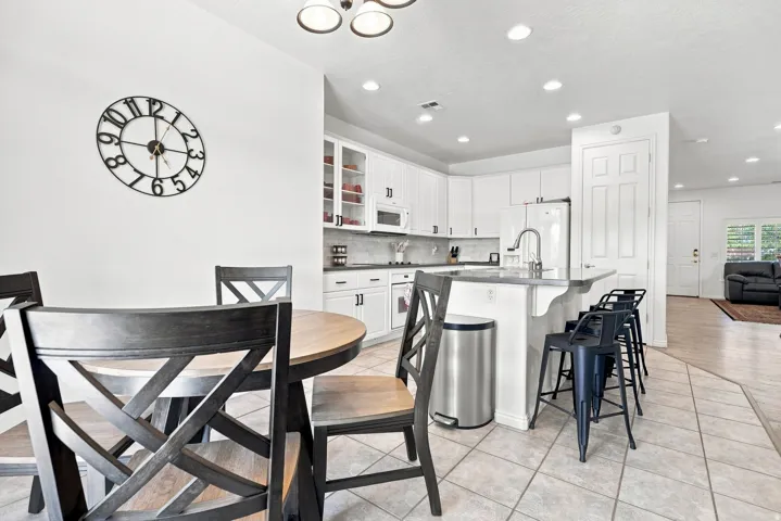 Kitchen featuring white cabinetry, light-toned countertops, a center island with bar seating, a stainless steel sink with a gooseneck faucet, and recessed lighting