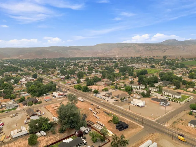 Expansive community featuring residential and commercial structures, mature trees, and mountainous terrain in the background
