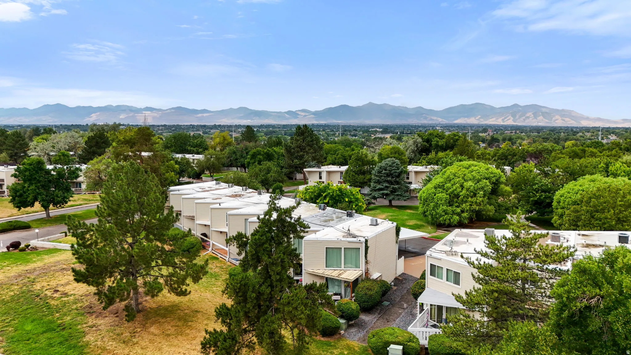 Expansive landscape featuring numerous multi-level residential structures with flat roofs, surrounded by mature trees and lush green spaces
