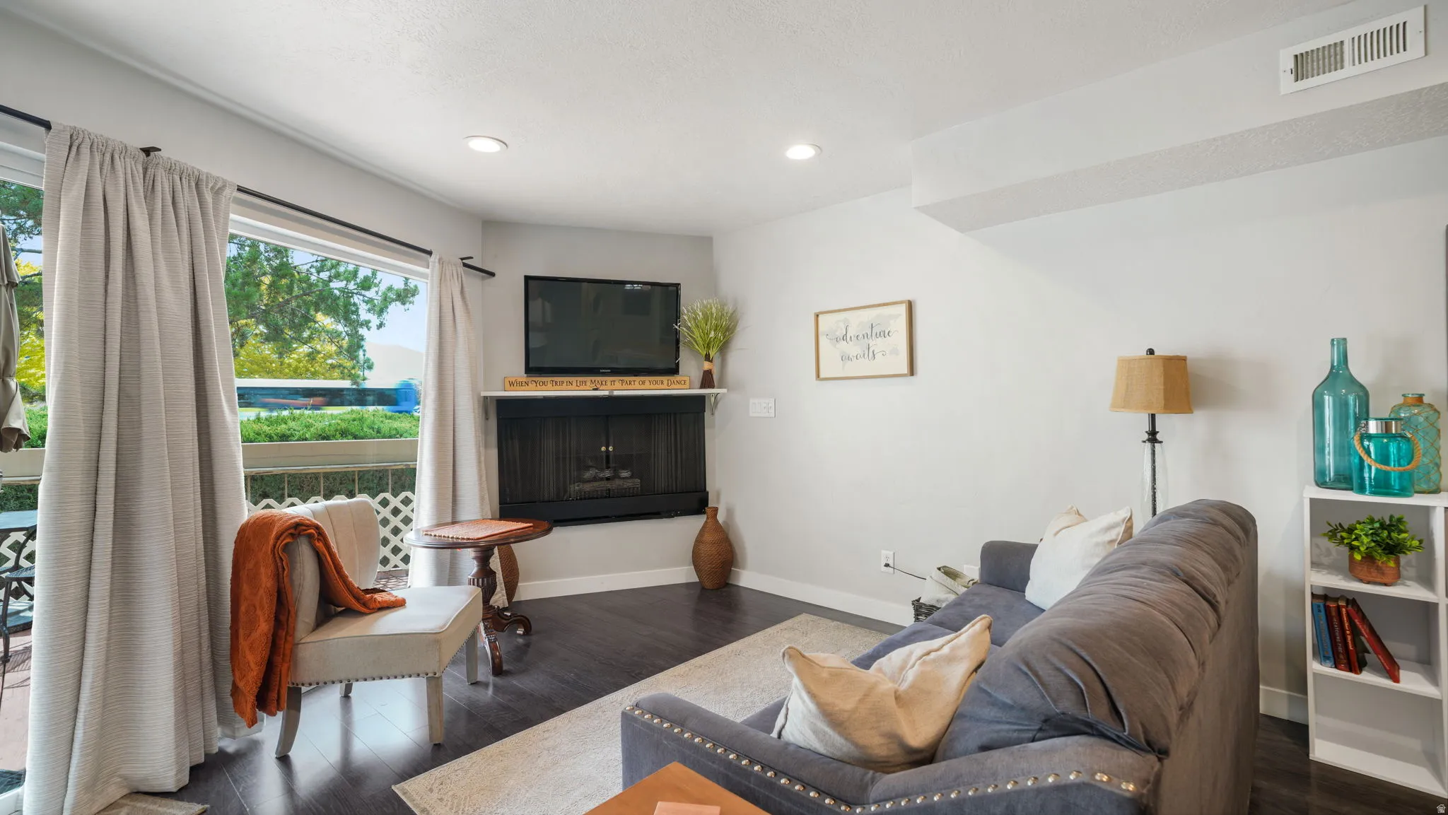 Spacious living area featuring wood-finish flooring, a corner fireplace with a white mantel, and a built-in media niche