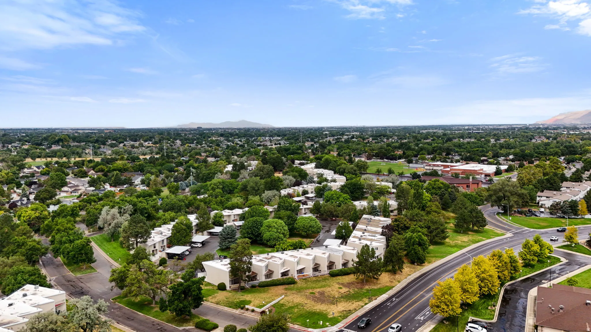 Expansive suburban landscape featuring mature trees, residential properties, and paved roadways