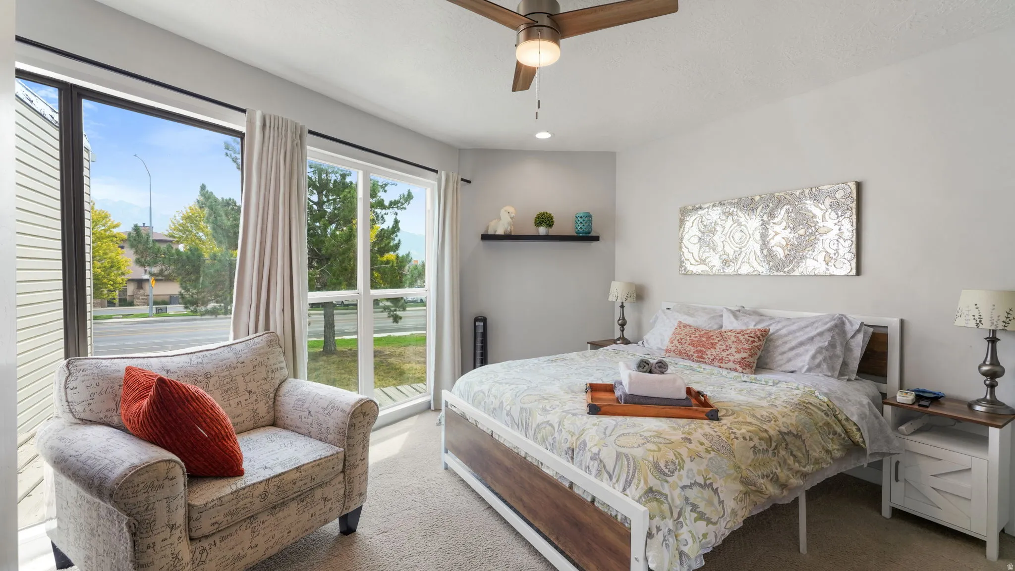 Bedroom featuring a ceiling fan, wall-mounted shelving, and carpeted flooring