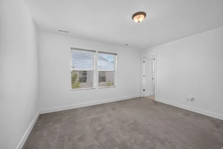 Neutral gray carpeting, white walls, and a flush-mount ceiling light