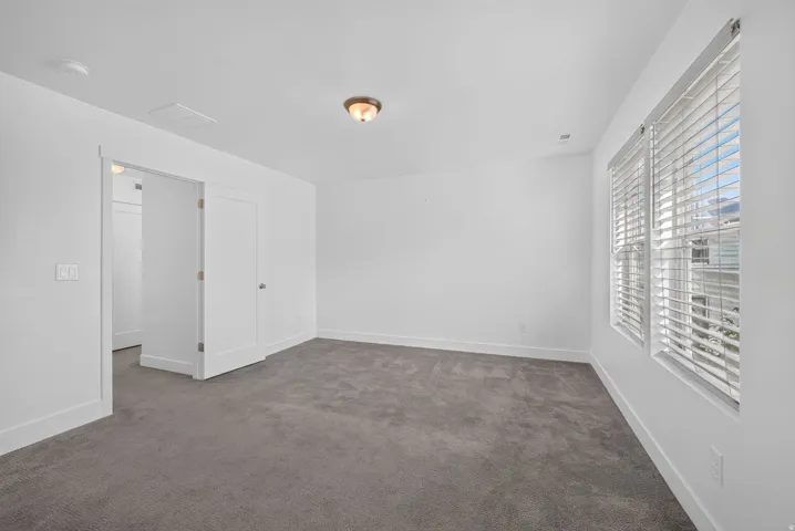 Plush gray carpeting, bright white walls, and a recessed window with blinds
