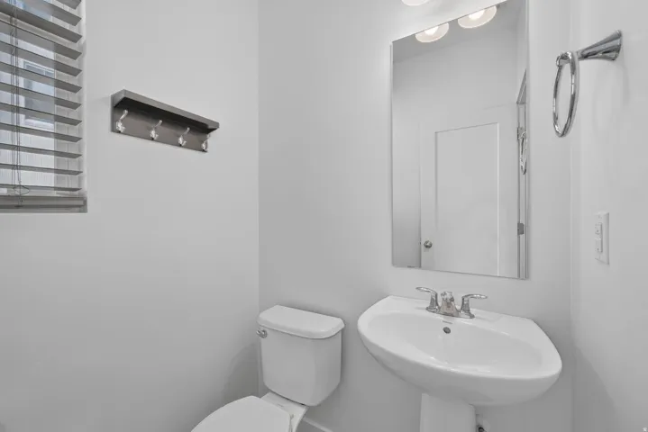 White pedestal sink with chrome fixtures and wall-mounted lighting