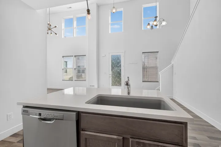 Kitchen island featuring an undermount sink, a stainless steel dishwasher, and a light-toned countertop