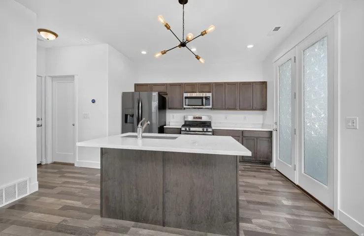 Kitchen featuring a central island with white countertop, dark wood-finish cabinetry, stainless steel appliances, and wood-finish flooring