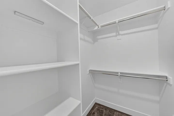 Walk-in closet with integrated lighting, multiple shelving units, and dual hanging rods