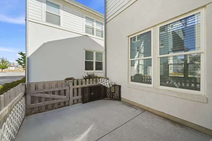 Picket fence with gate, concrete patio, stucco exterior, and multi-pane windows