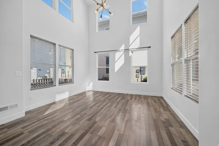 High ceilings with clerestory windows, wood-finish flooring, and multiple windows with blinds