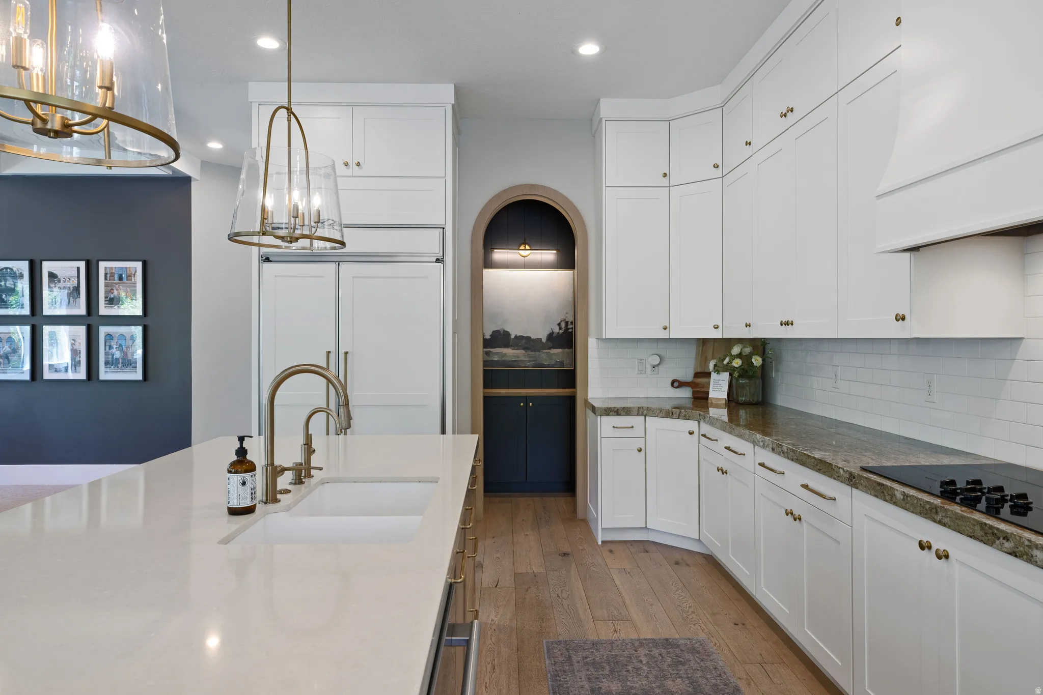 Remodeled kitchen featuring white shaker cabinetry, brass hardware, and light wood-finish flooring