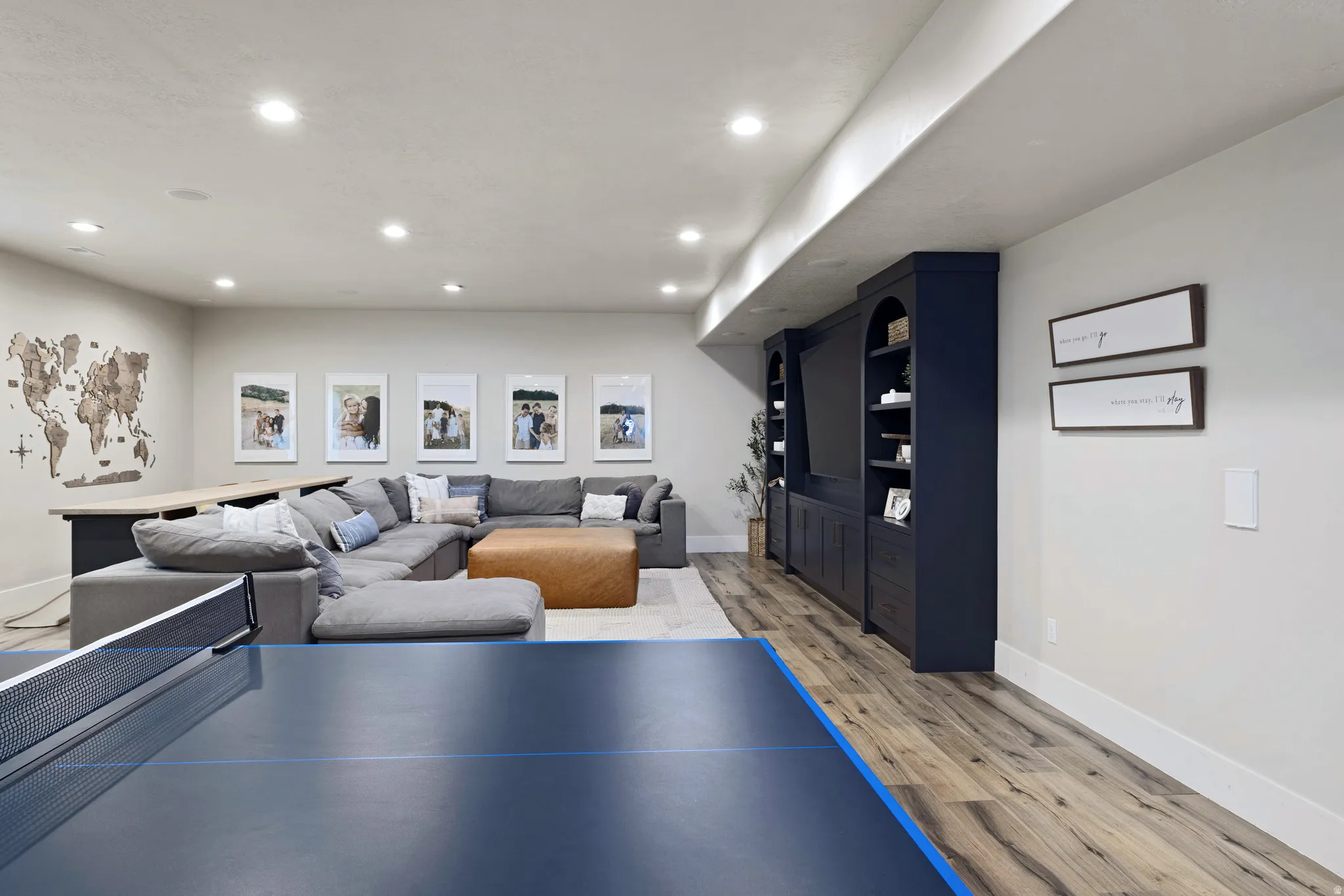 Spacious entertainment area featuring LVP flooring, recessed lighting, and a built-in media console with extensive cabinetry