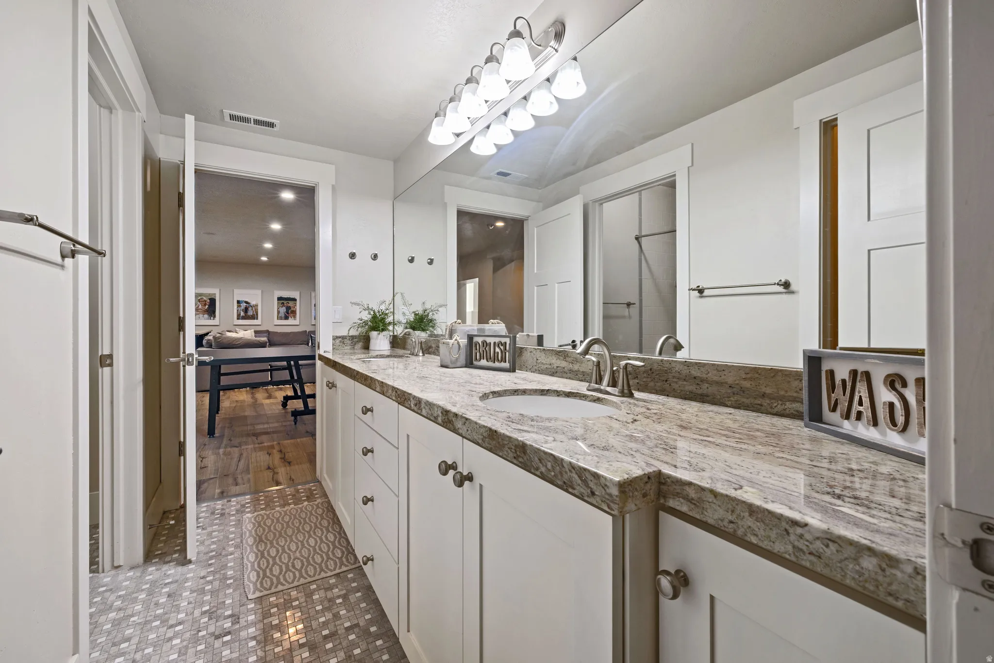 Double vanity featuring an undermount sink, stone countertop, and brushed nickel faucet