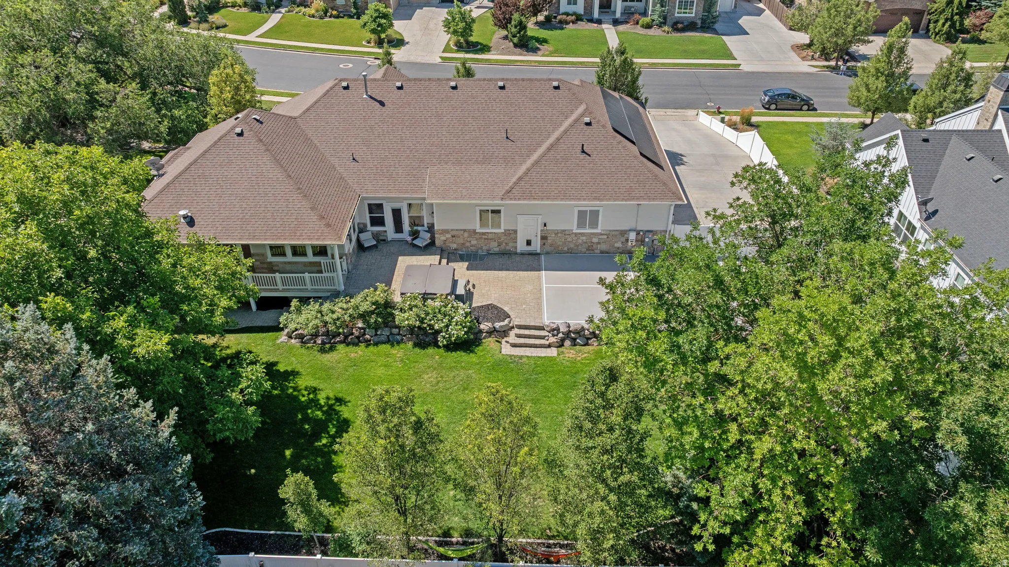 Rear exterior featuring a stone and siding facade, a covered patio, and an open paver patio