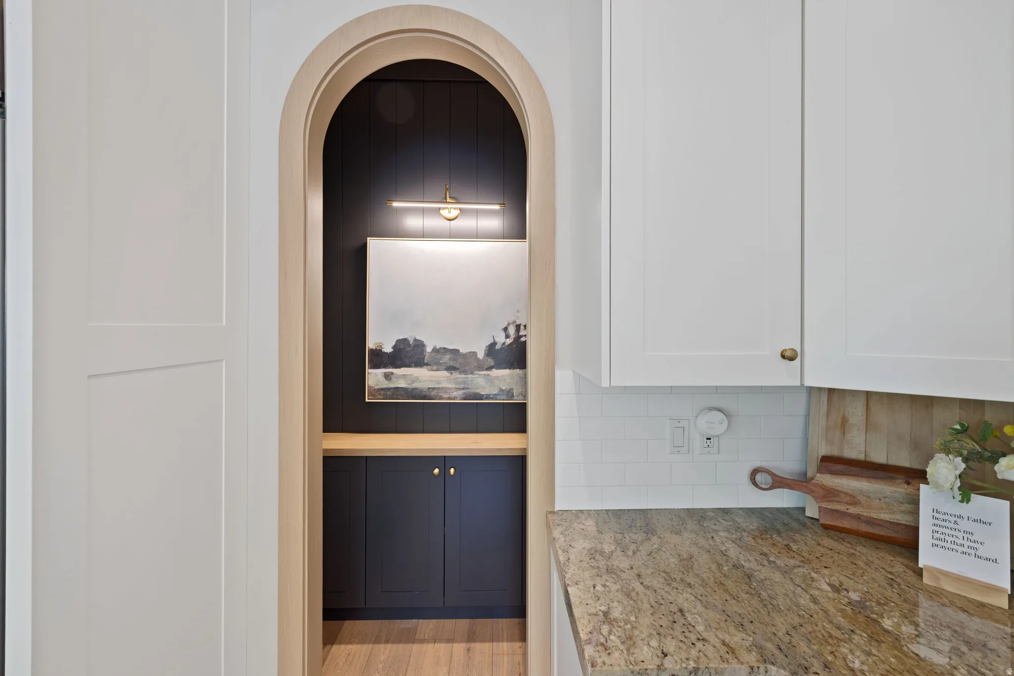 Archway entry to the pantry with oak wood trim and dark paneled interior wall
