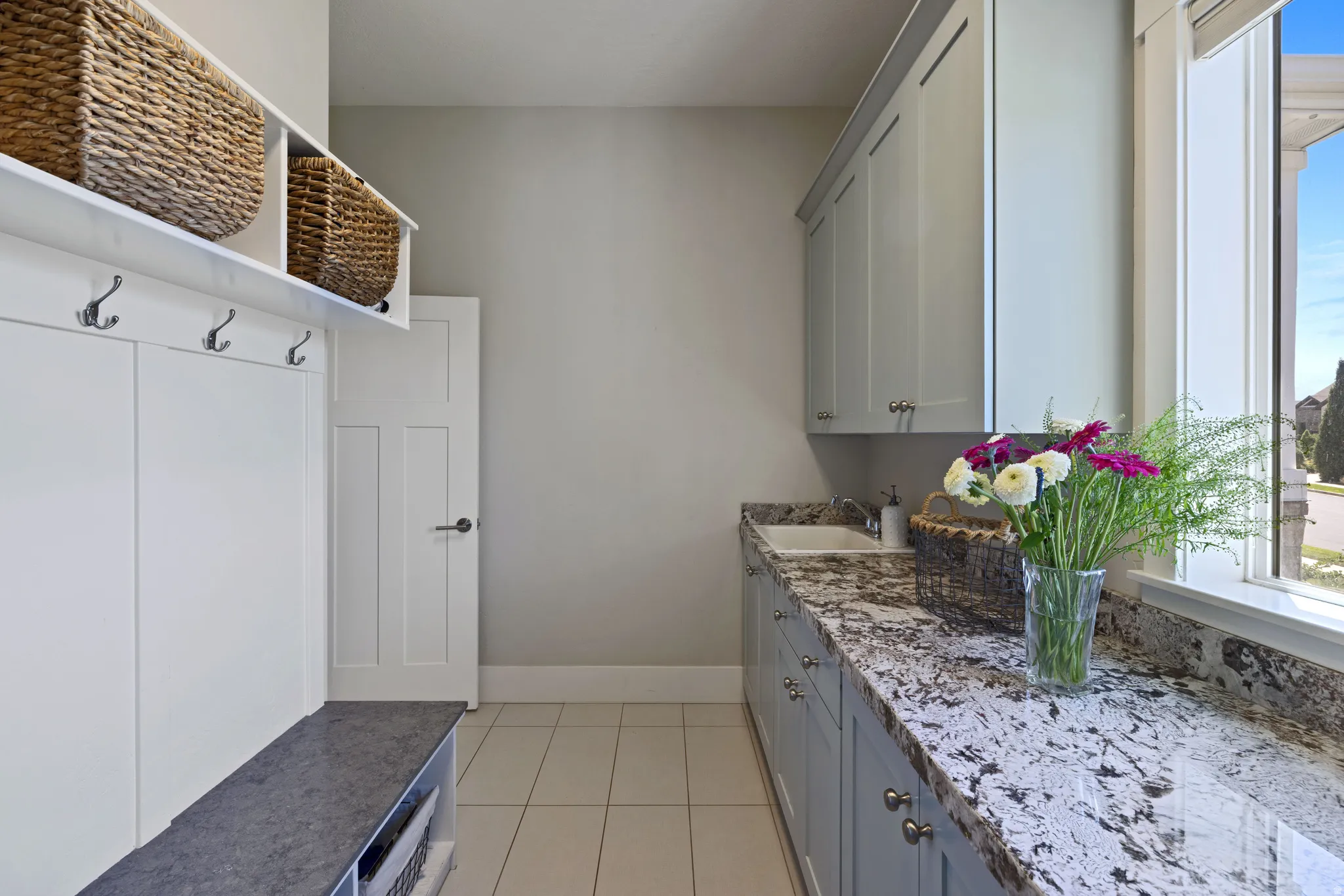 Laundry room featuring a built-in bench with storage, coat hooks, and overhead shelving