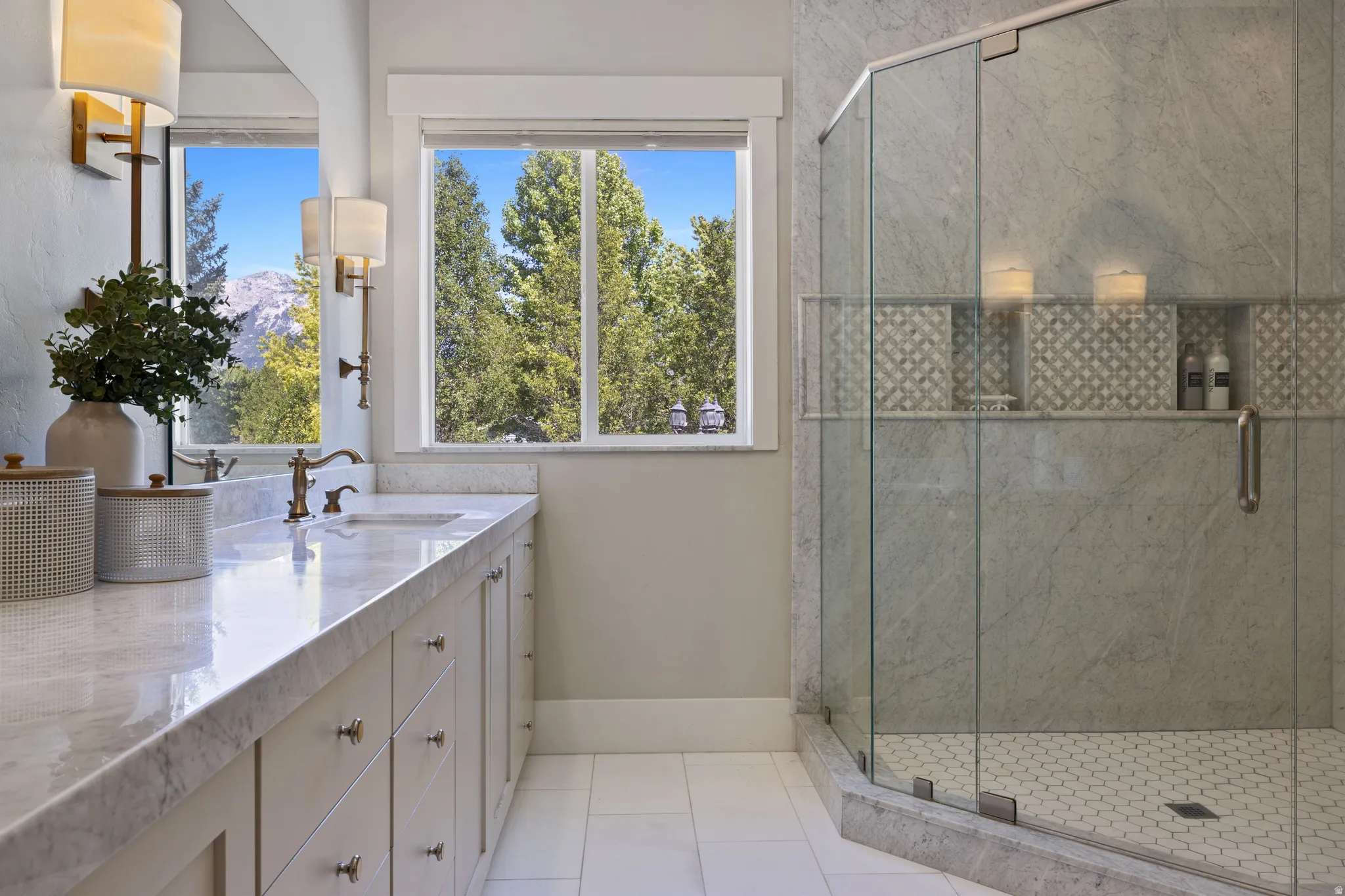 Primary bathroom featuring a double vanity with polished stone countertops, under mount sinks, and bronze-finish fixtures