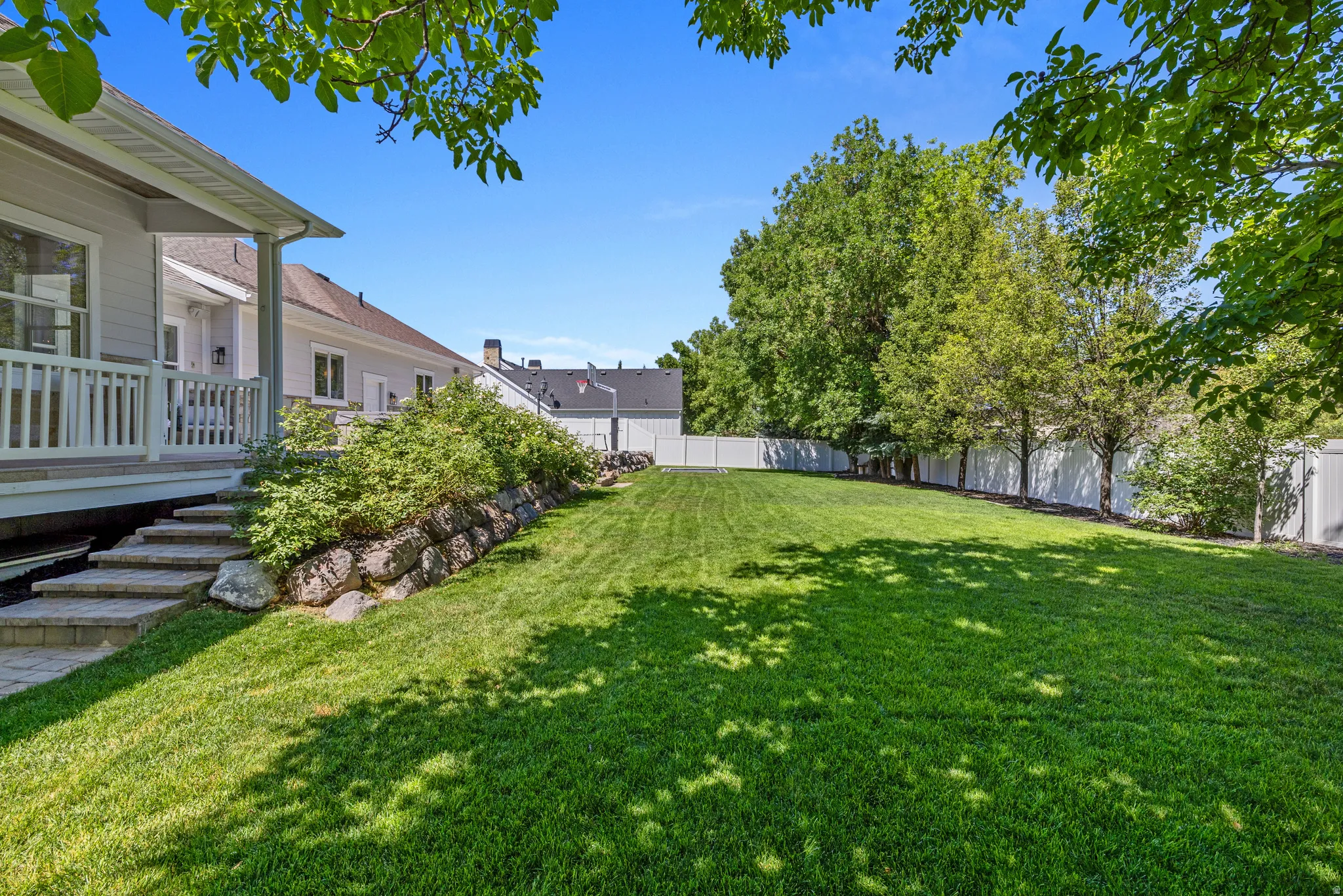 Expansive green lawn with a white privacy fence