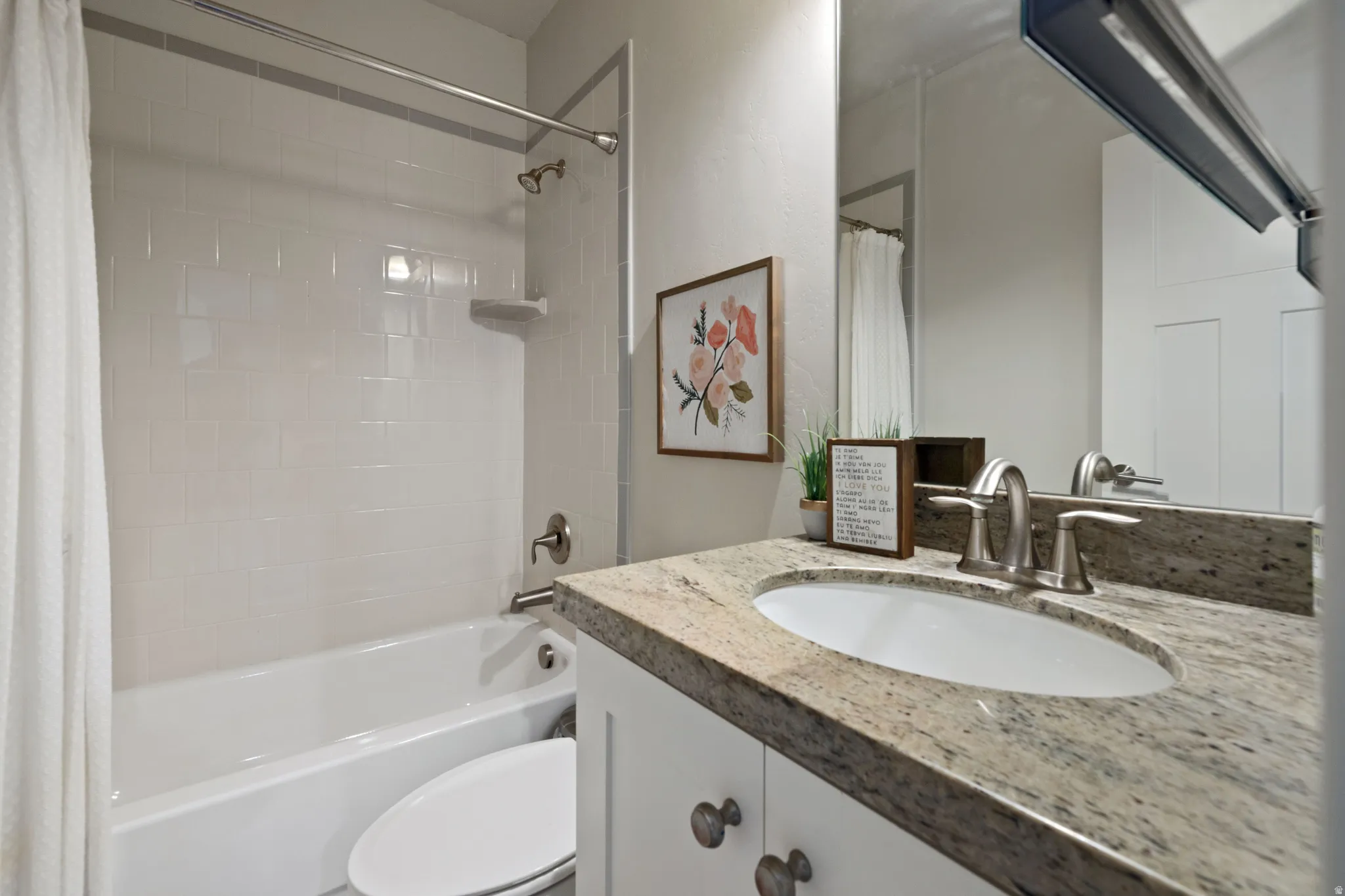 Bathroom featuring a white bathtub, subway tile surround, granite countertop, undermount sink, and brushed nickel fixtures