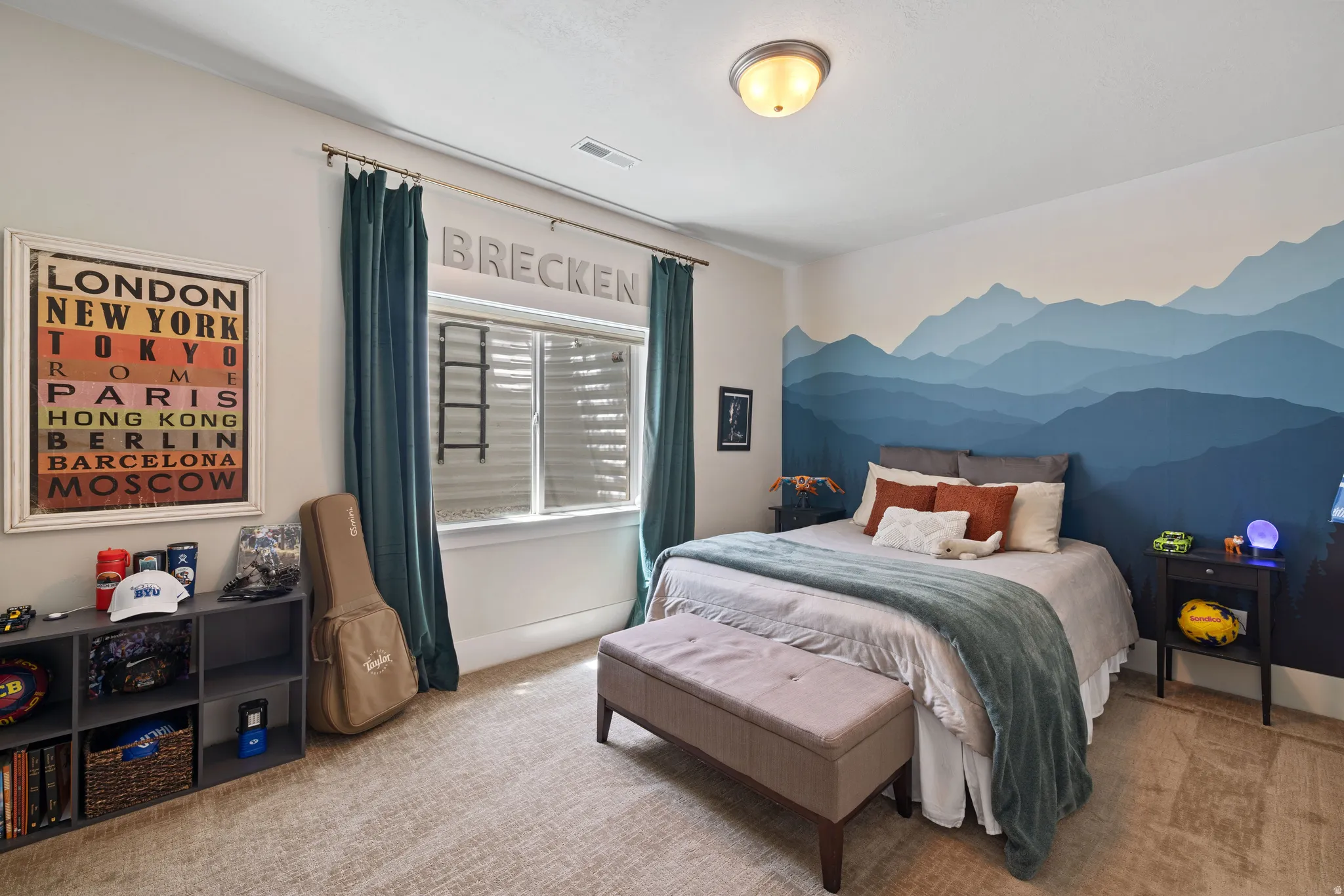 Bedroom featuring a multi-toned mountain mural wall, a window with blinds and dark teal drapes, and neutral-toned carpeting